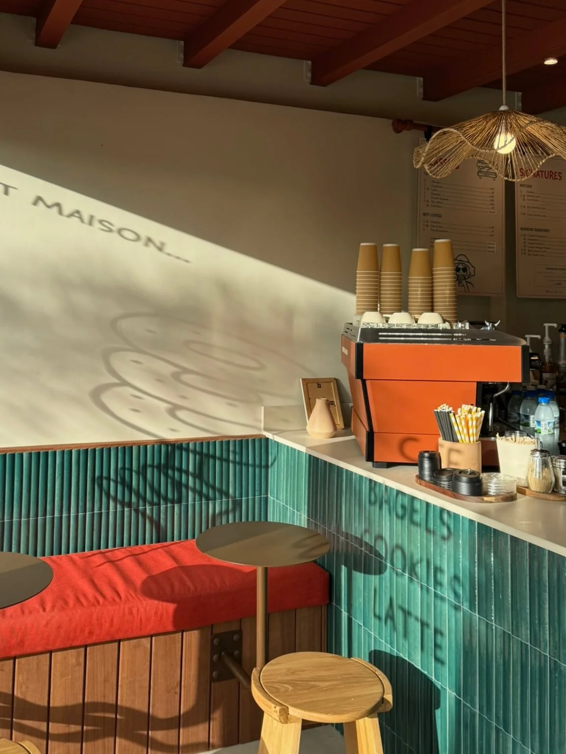 Banquette aux coussins rouges le long du comptoir carrelé — Dado Café