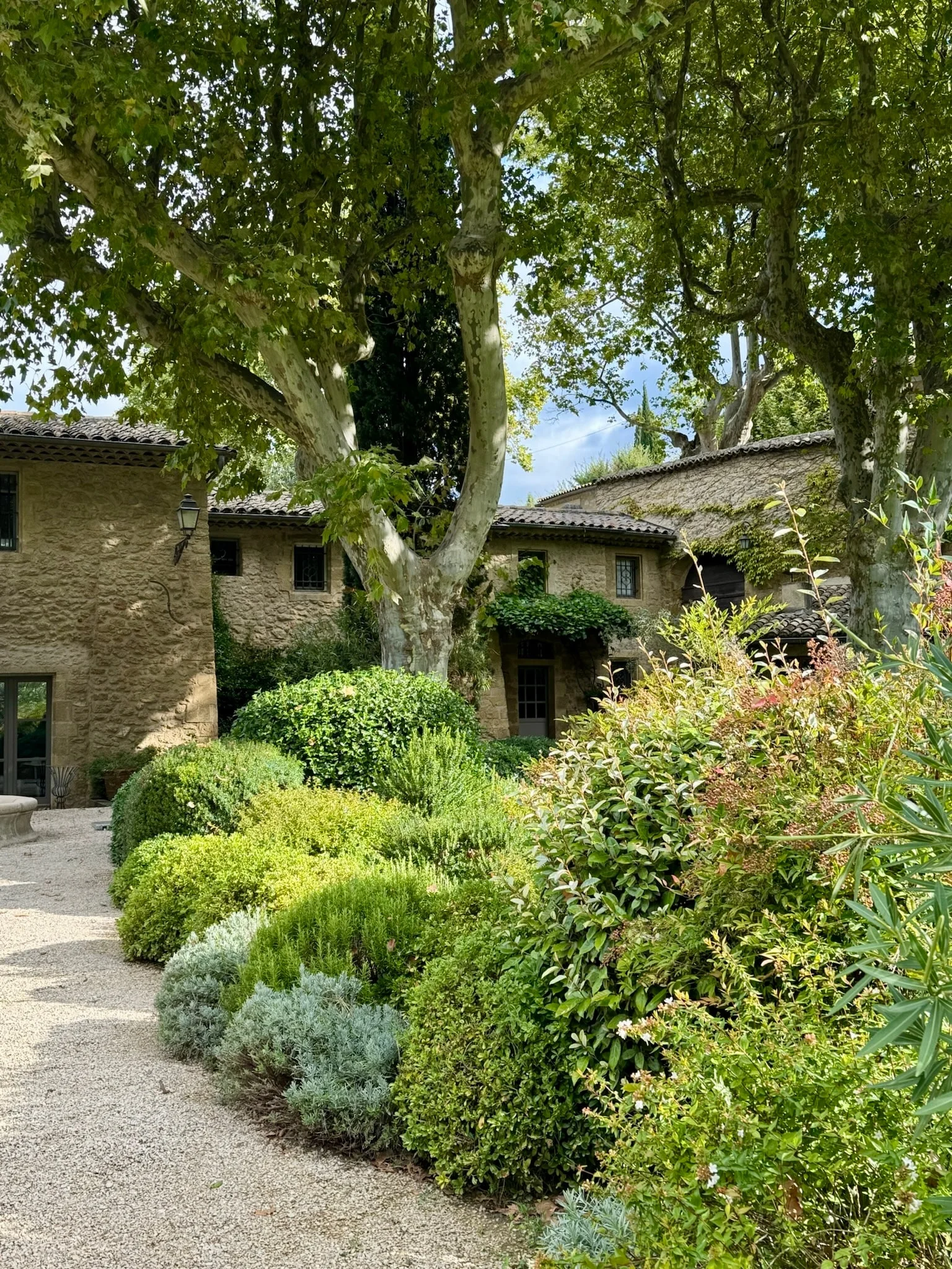 Stone facade of the house among plane trees and a Mediterranean garden — Fontaine