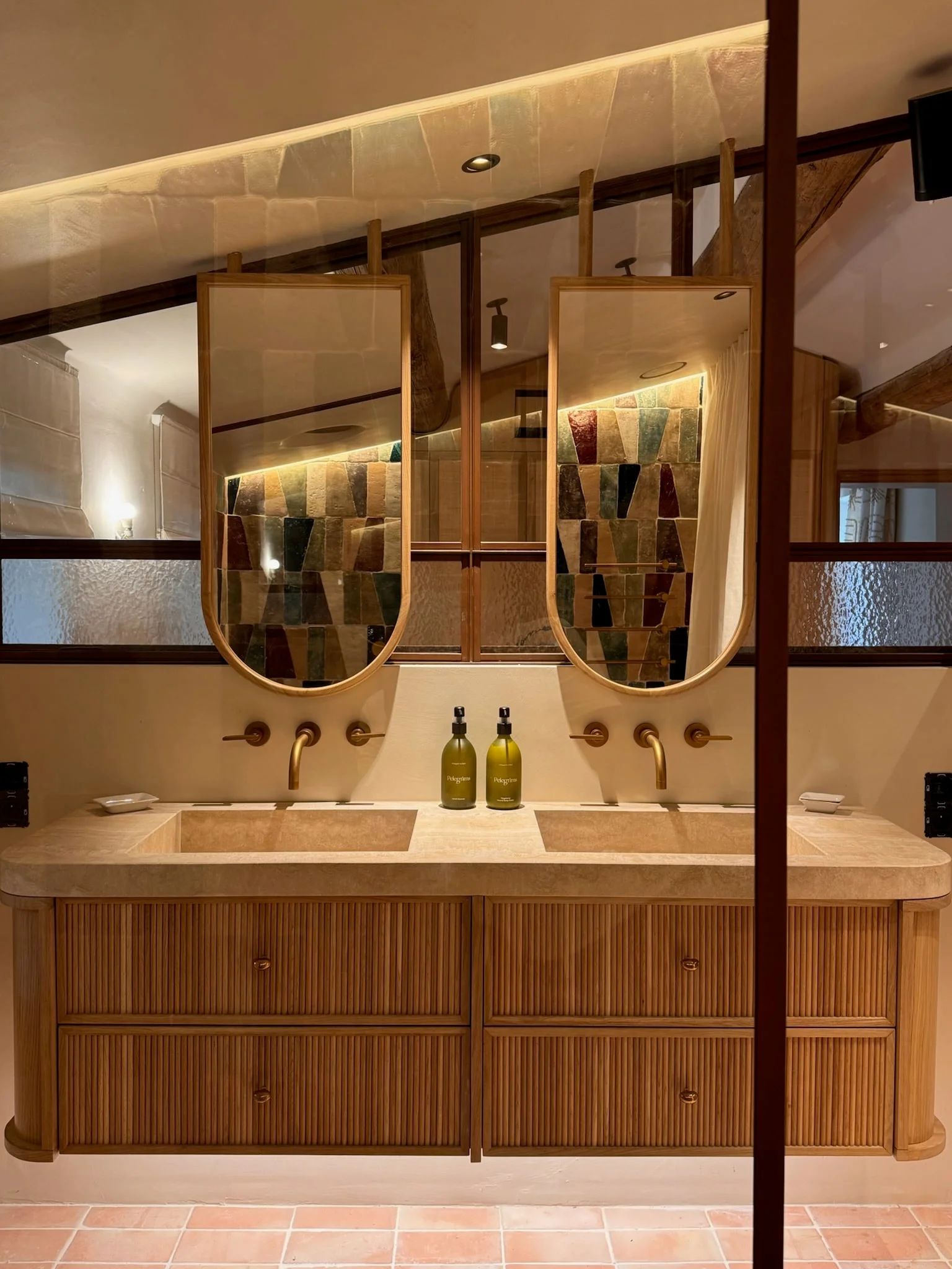 Double vanity with oak drawers, oval mirrors and multicoloured tiles — Fontaine