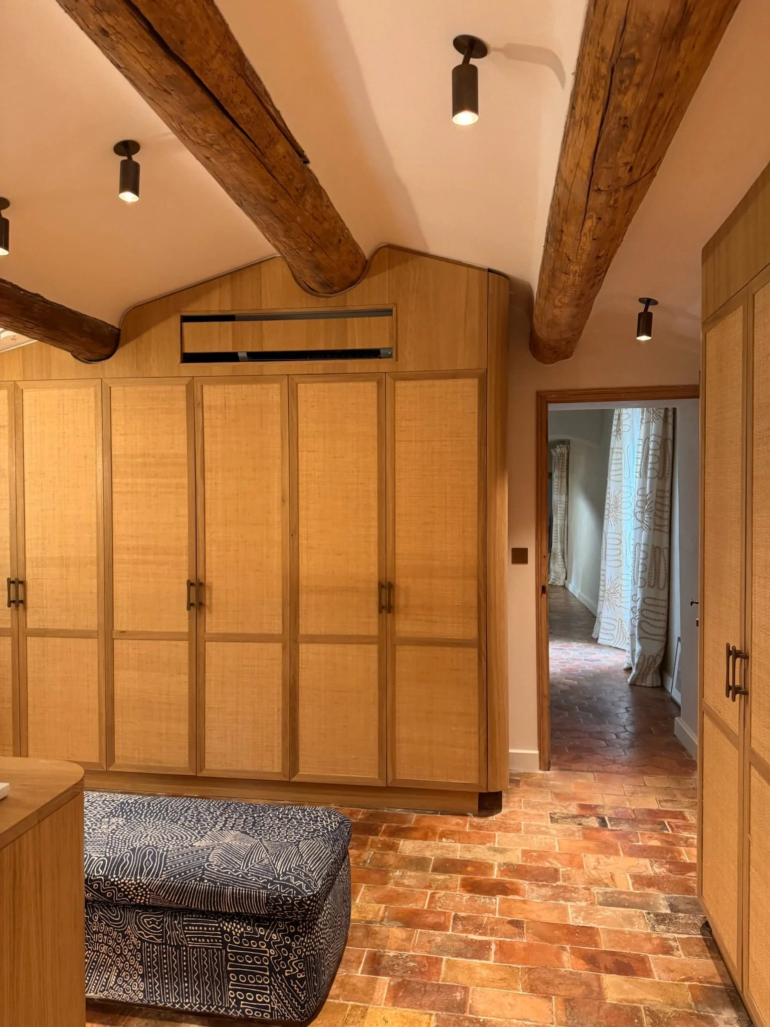 Bedroom with cane wardrobes, exposed beams and terracotta floor — Fontaine