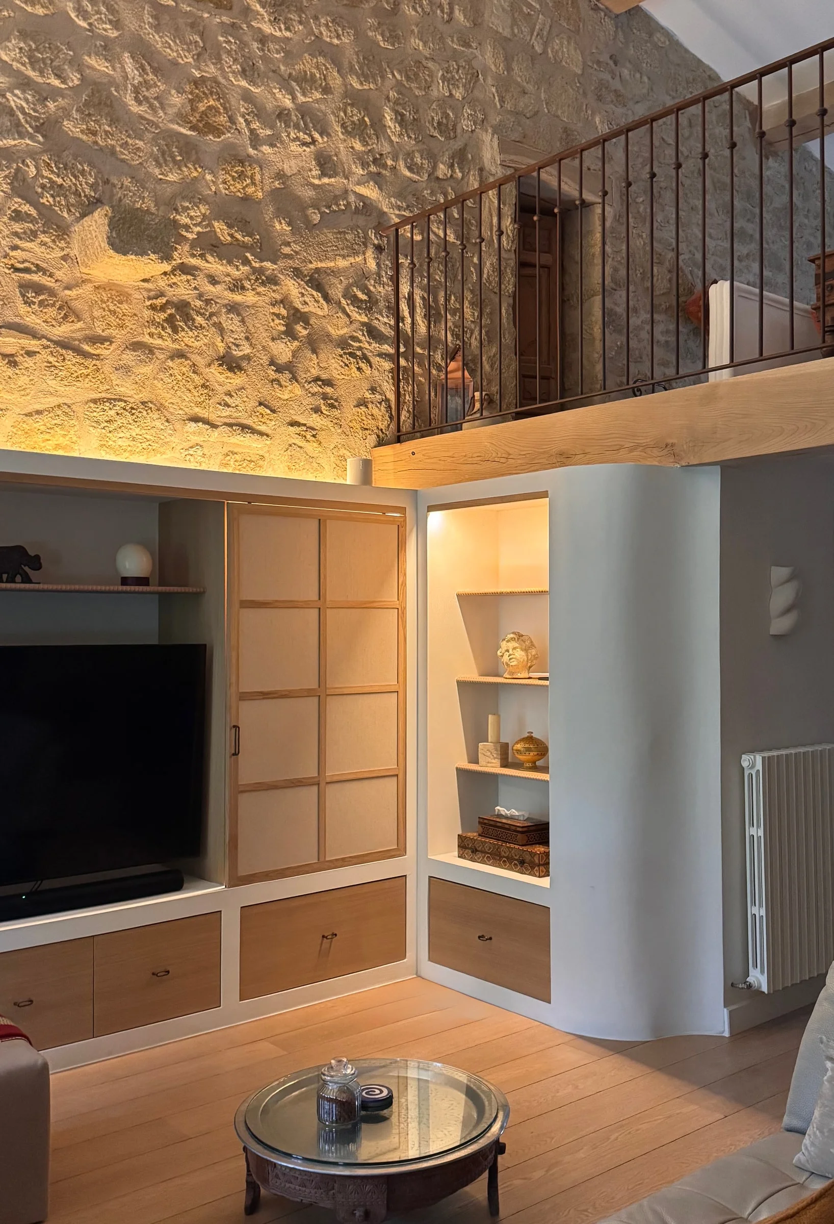 Living room with exposed stone wall, mezzanine and built-in shelving — Fontaine