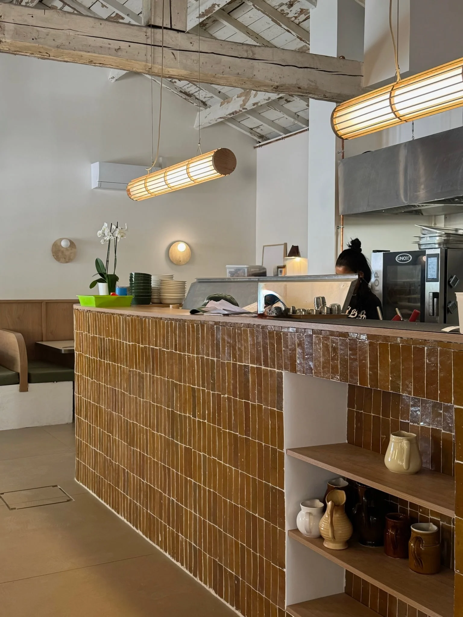 Ochre zellige counter beneath the original timber roof — Honoré Brunch